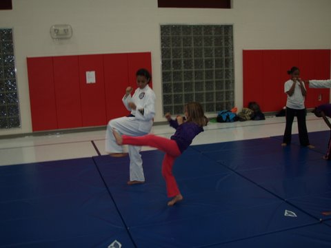 Erika Tucker-Owens working with new student Nia on basic kicks